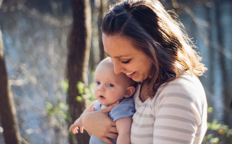 femme portant un bébé près des arbres