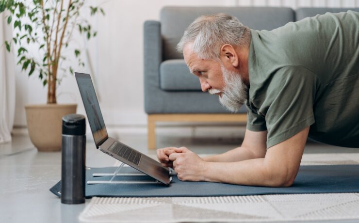 An Elderly Man Working Out while Looking at the Laptop yoga