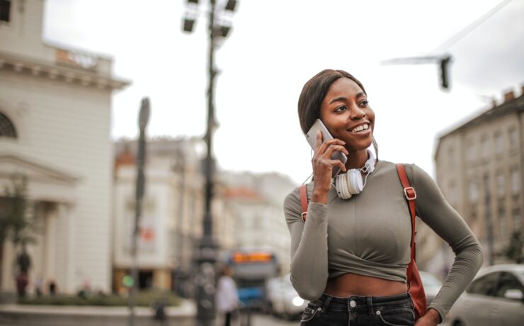 Jeune fille souriante téléphonant en marchant dans la ville