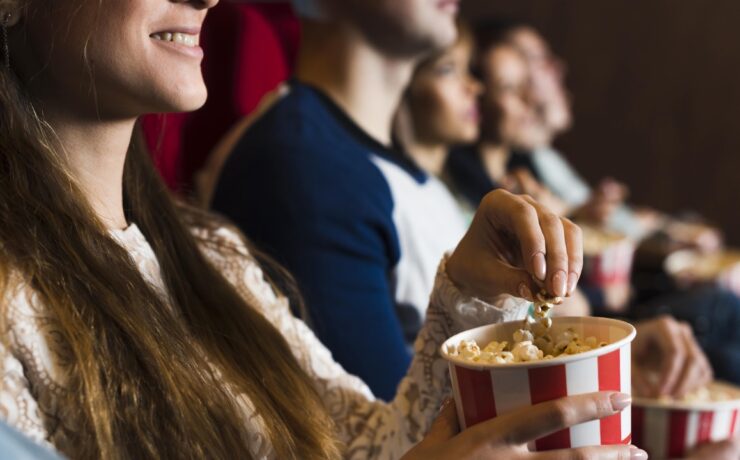 personnes au cinéma, fille souriant en mangeant du pop-corn