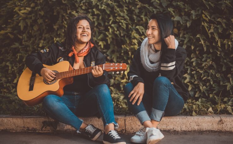 femme jouant de la guitare assise à côté d'une femme souriante