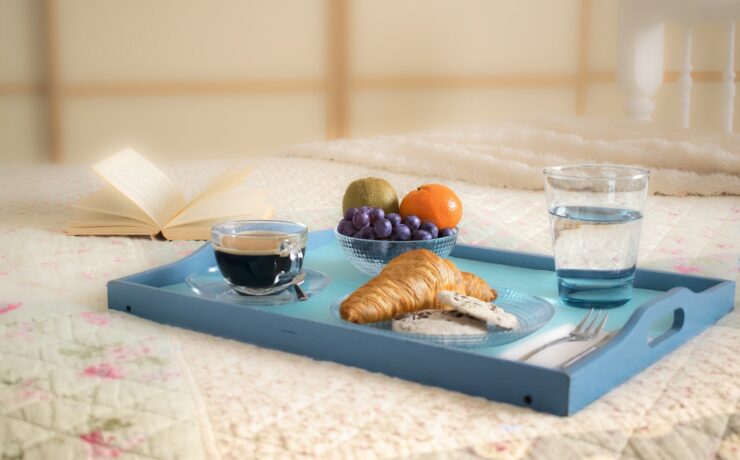 plateau bleu sur une table avec croissant, café, verre d'eau