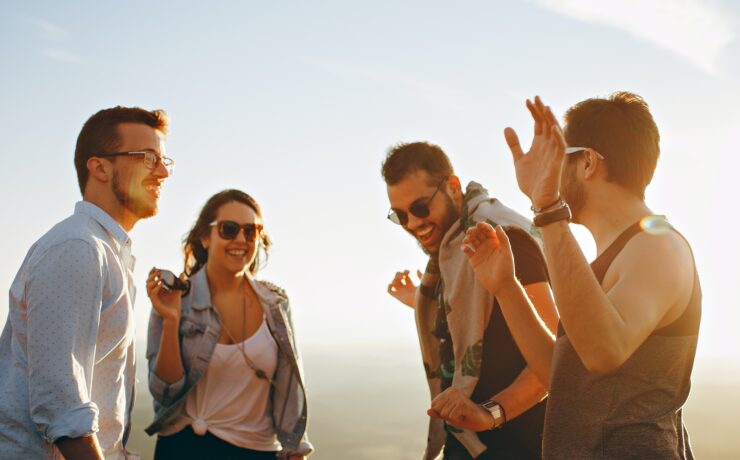 trois hommes et une femme souriant et s'amusant ensemble