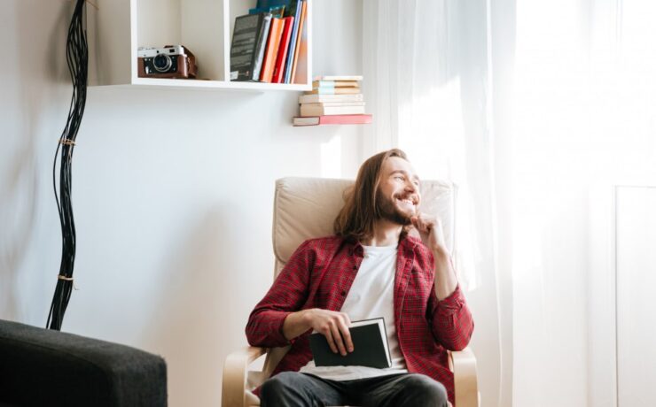 homme barbu souriant avec un livre