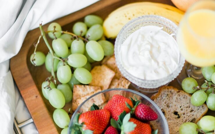 variété de fruits avec yaourt ou fromage sur un plateau en bois